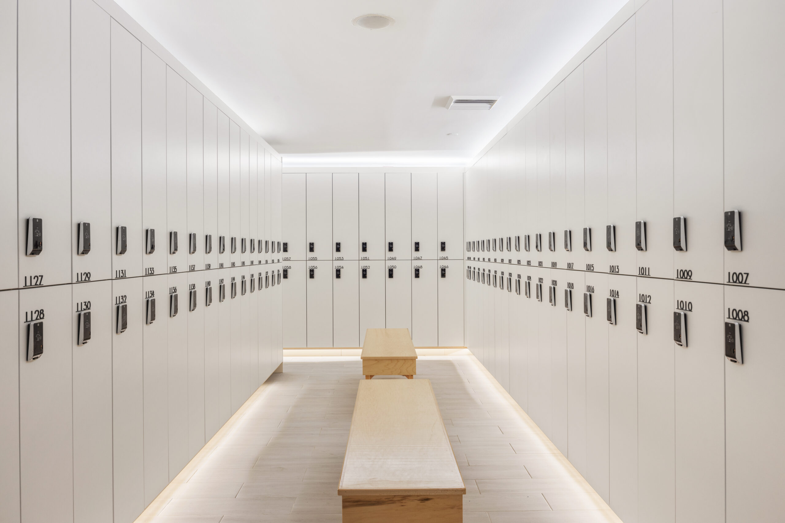 inside the locker room isle, featuring benches and closed white lockers